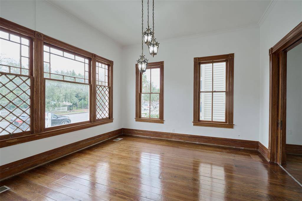 Explore the spacious living area featuring a stunning historic front window with diamond grid pattern, elegant lighting, and beautiful wooden pocket doors for added privacy. The charming wood floors complete the timeless appeal.