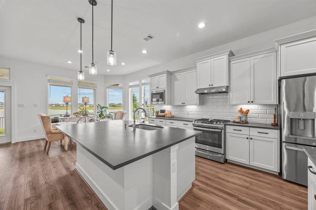 This beautiful kitchen boasts 42" cabinets, elegant LVP vinyl flooring, a spacious island with storage, and stunning lighting.