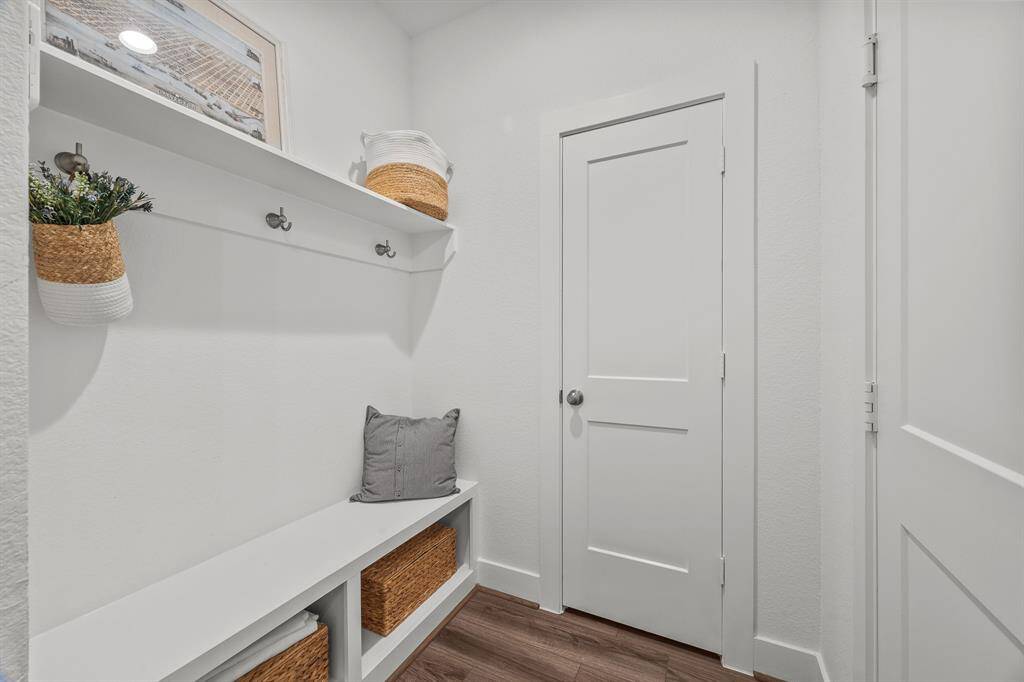 Spacious mudroom off the three-car garage, featuring a cozy sitting area and ample storage.