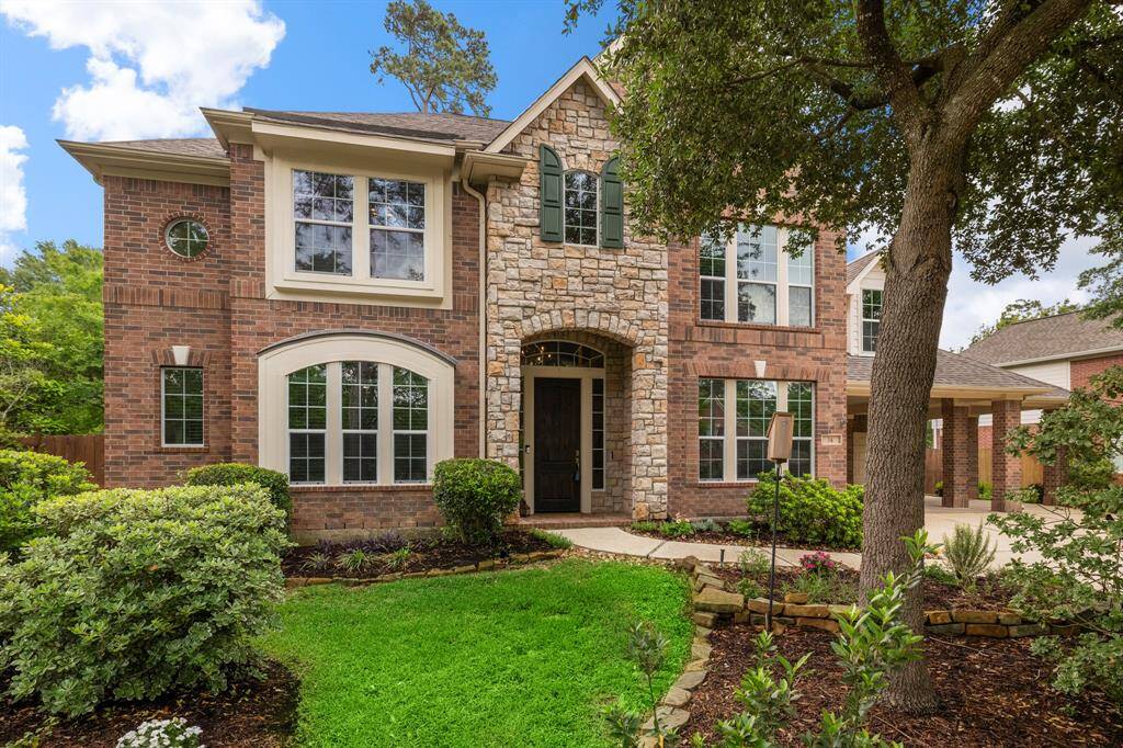 Charming two-story home featuring a brick and stone elevation, large windows for ample natural light and a beautifully landscaped yard with mature trees. The welcoming front entrance adds to the curb appeal.