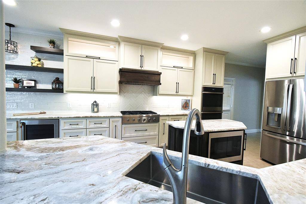 The open shelving and stylish light fixture add character to this kitchen.  The lighting is bright and highlights the spacious and functional design.