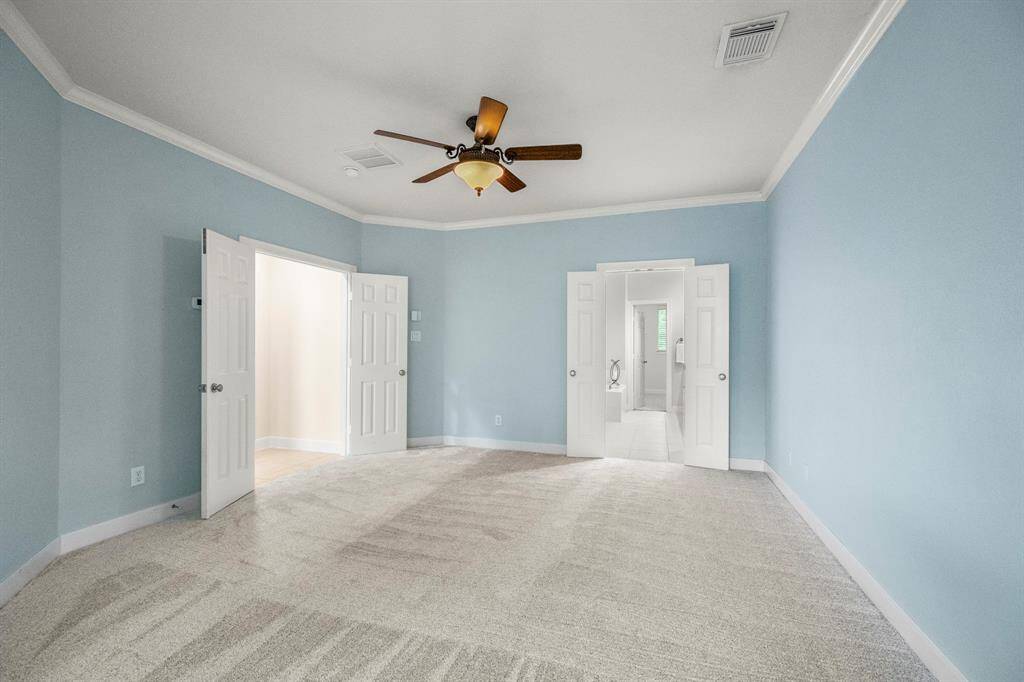 Oversized primary suite with new carpeting and double doors leading into primary bath.