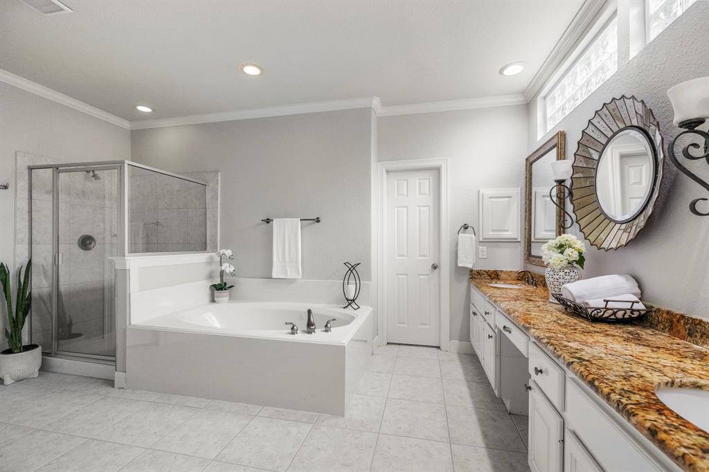 Relaxing primary bathroom features a large soaking tub, separate glass enclosed shower, dual sinks and granite countertops.  His and hers closets offer functional organization and dedicated space.