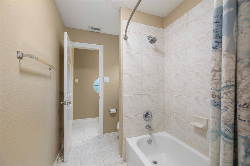 Sparkling clean Jack and Jill bathroom offering neutral tile and shower tub combo.