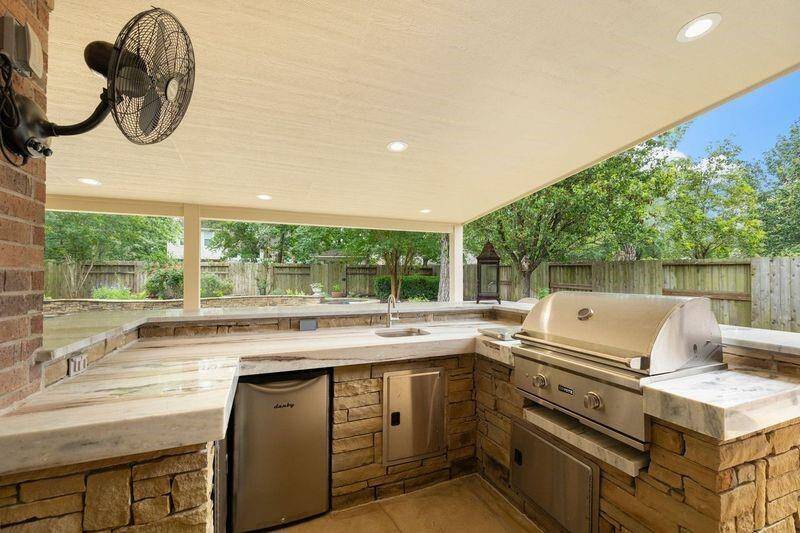 The outdoor kitchen has everything you will need for an enjoyable grilling experience -- a new grill, side burner, sink, and a new mini fridge. The Quartzite countertops offer ample space to place food for parties.