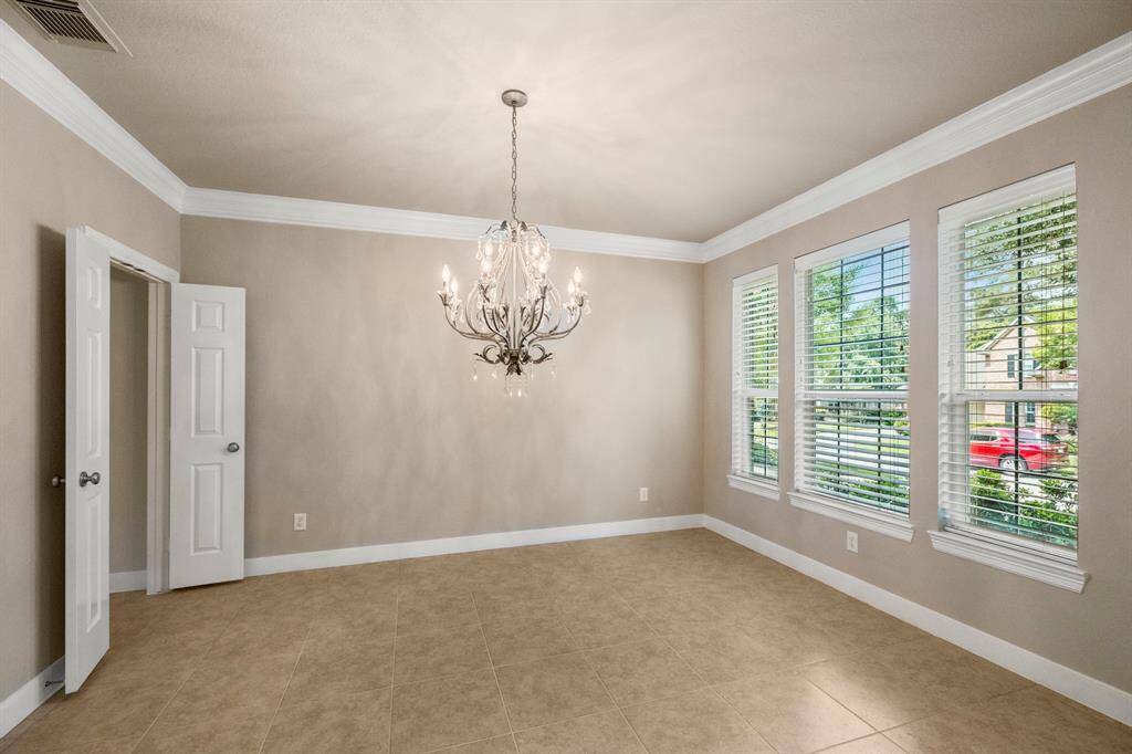 Formal dining room with large windows and neutral walls.