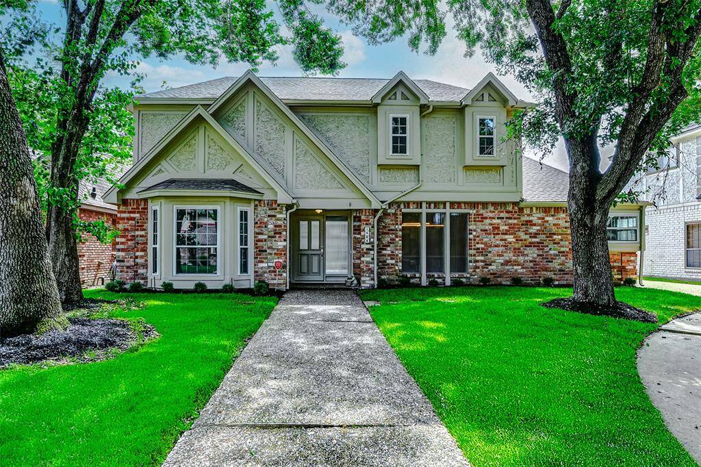 This charming two-story home features a classic brick facade with Tudor-style accents. Large windows and a well-maintained front lawn offer inviting curb appeal, while mature trees provide shade and character.