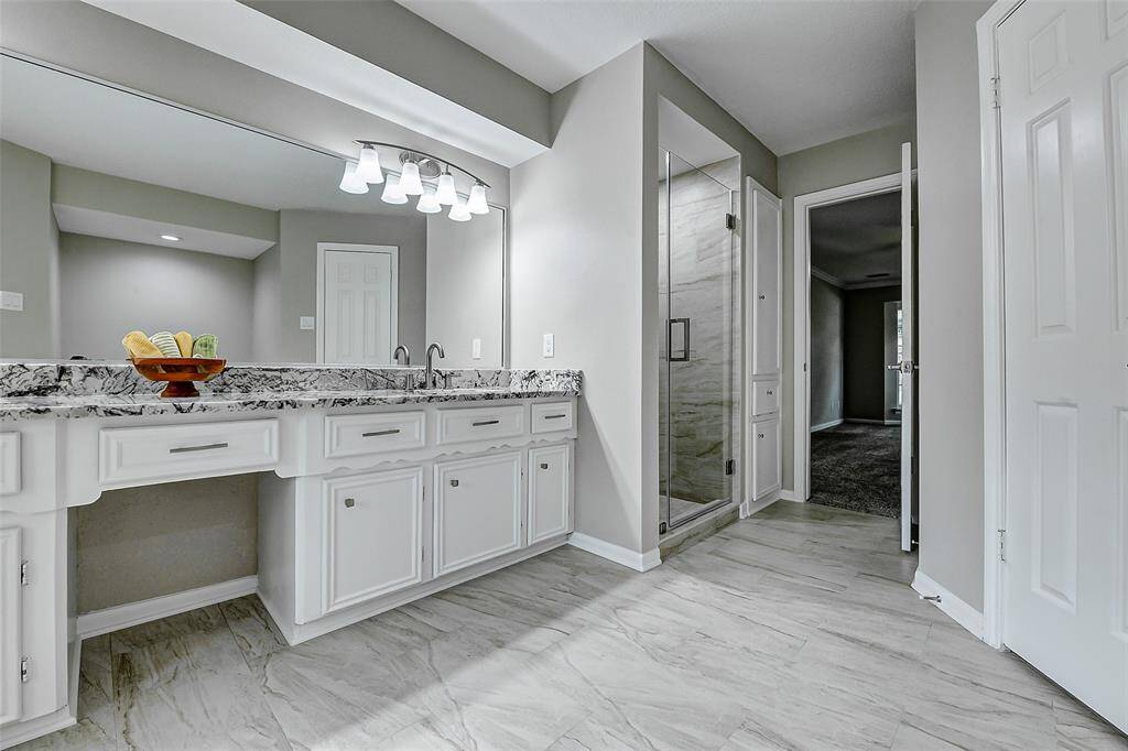 Light and bright primary bathroom with freshly painted cabinets, granite countertops and updated shower.