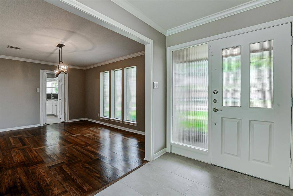 Dining room features rich wooden flooring, large windows for natural light, and a stylish hanging light fixture.