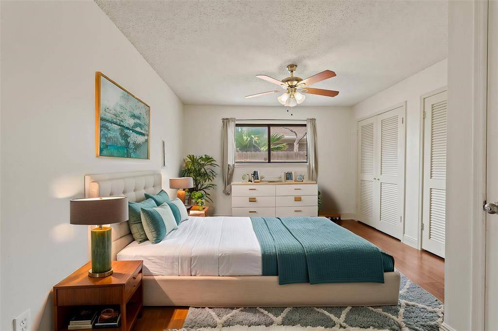 Virtually Staged: Secondary bedroom with hardwood floors, built-in closet, large windows, and a ceiling fan.
