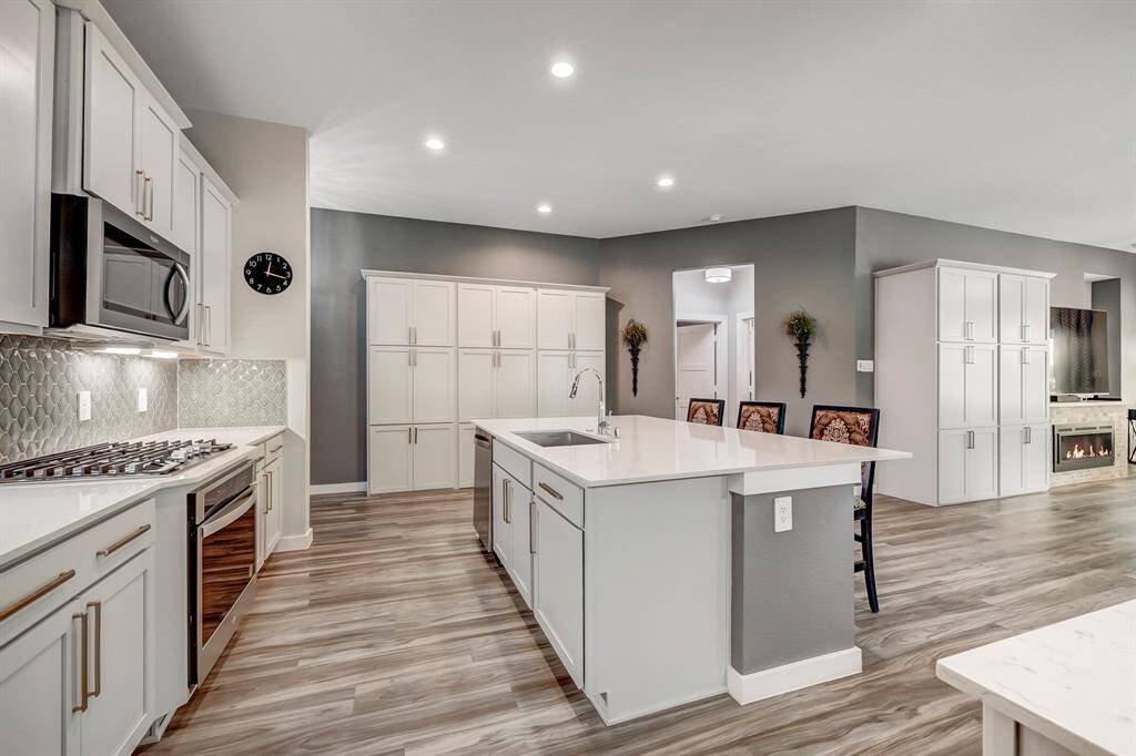 Entertainers Kitchen features quartz countertops, oversized sink, stainless steel appliances, gas cooktop and built in oven.