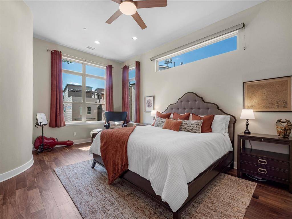 Generous dual primary bedroom with large windows that fill the space with natural light. Features warm hardwood floors and a layout that offers flexibility and comfort, complemented by tasteful design details throughout.