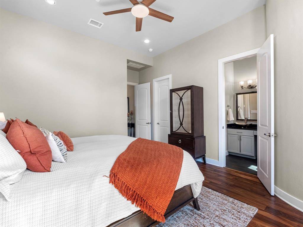 Primary bedroom with warm wood flooring, neutral tones, and a ceiling fan for year-round comfort. Offers direct access to a modern ensuite bathroom and provides a calm, well-proportioned space ideal for rest and relaxation.