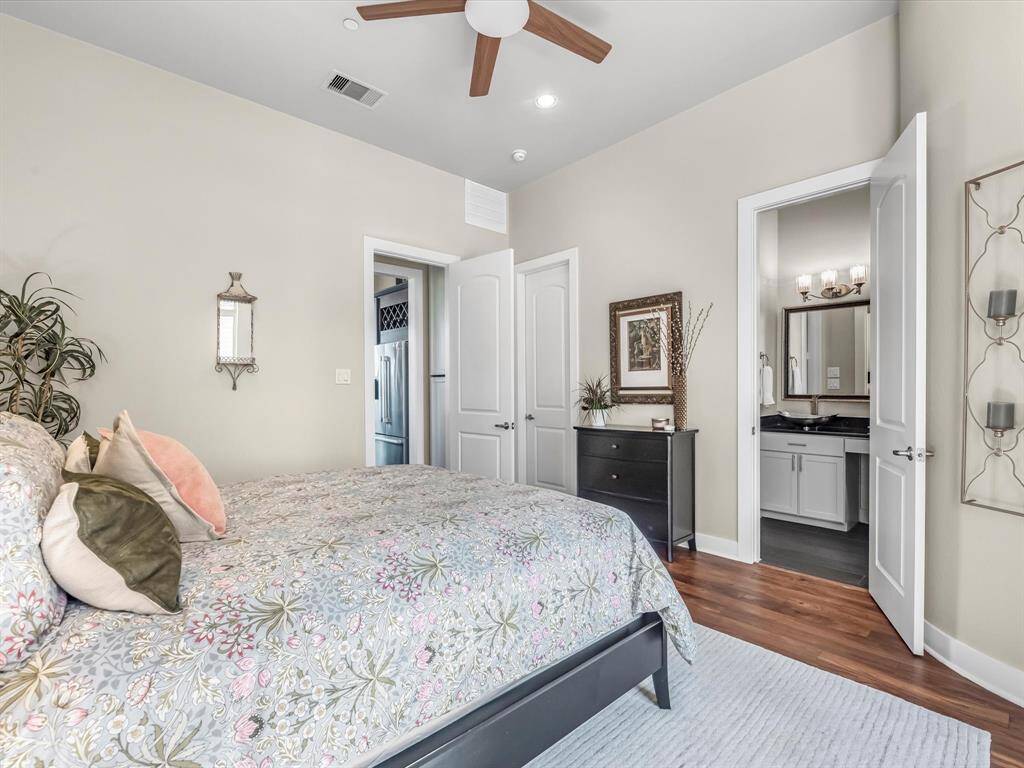 Dual primary bedroom with hardwood floors, neutral tones, and a ceiling fan for added comfort. Includes a private ensuite bath featuring modern fixtures and dual vanities for everyday convenience.