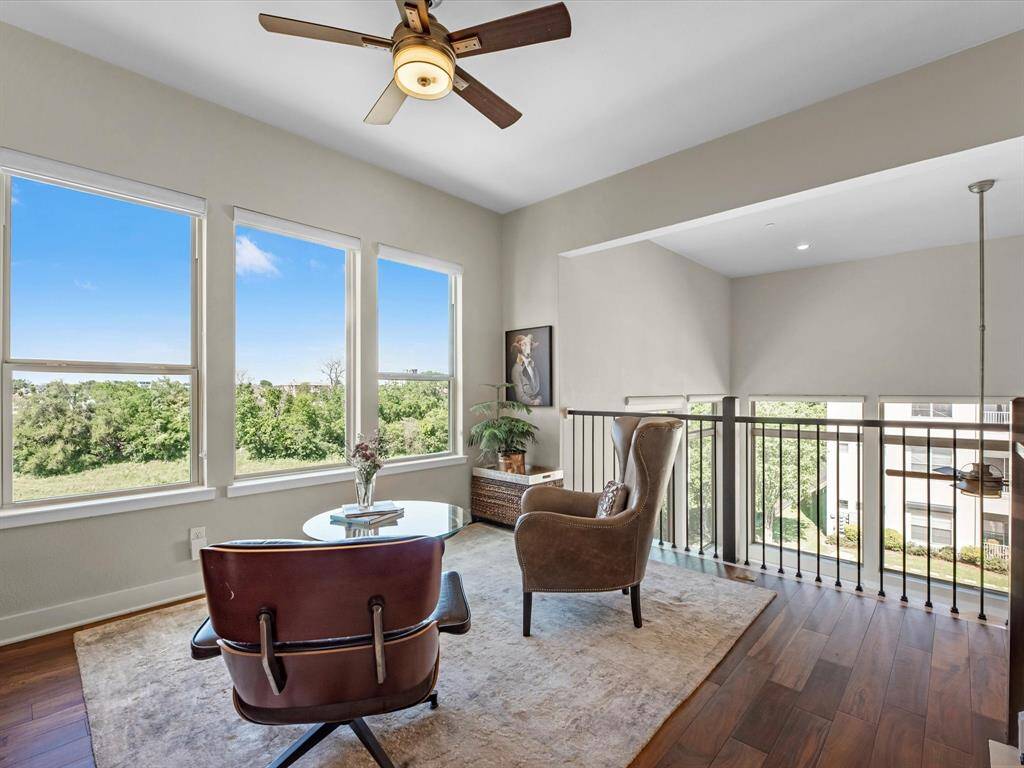 Inviting loft area features large windows offering scenic views, hardwood floors, and a ideal for seating arrangement.