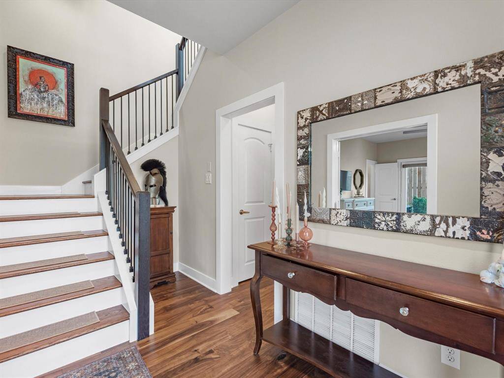 Welcoming entryway located on the first floor, featuring rich wood flooring and a staircase with a dark, modern railing.
