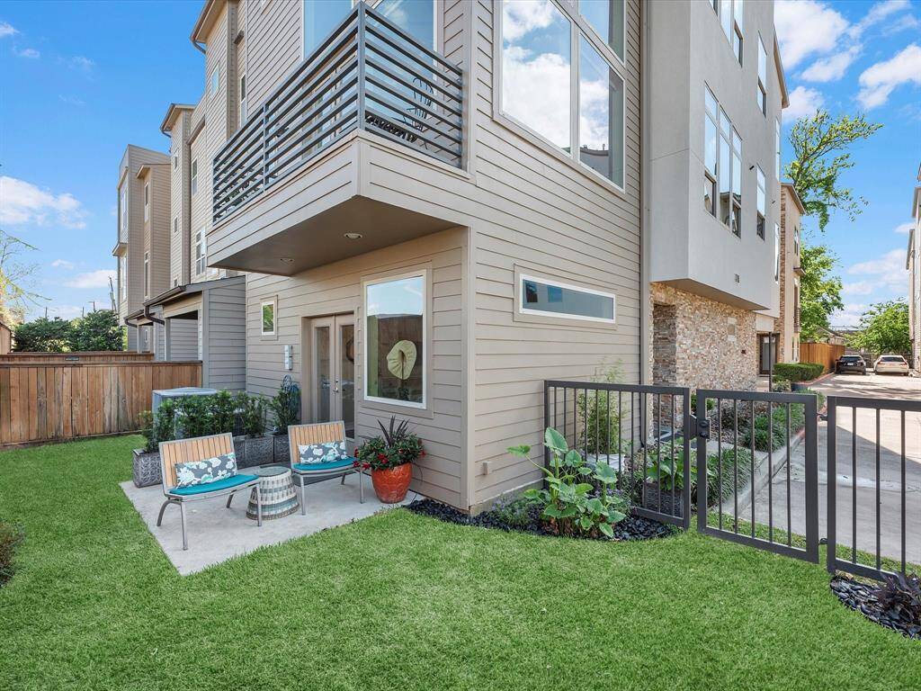 Stylish multi-story home with a private fenced yard and inviting patio. Highlights include a charming seating area, manicured lawn, and sleek modern exterior—ideal for relaxing or entertaining outdoors.