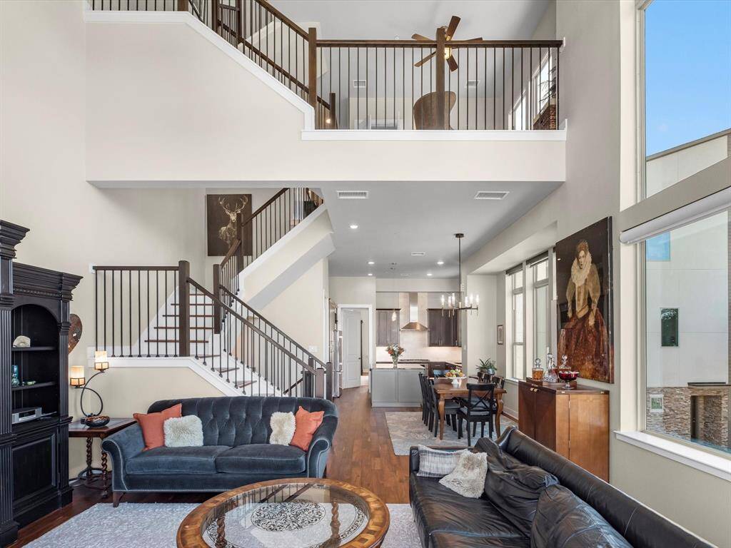 Expansive living area with impressive ceiling height and a wide open layout that connects effortlessly to the kitchen and dining spaces. Oversized windows flood the room with natural light, while a striking staircase leads to an upper-level balcony. The scale of the space offers flexibility for both everyday living and entertaining.