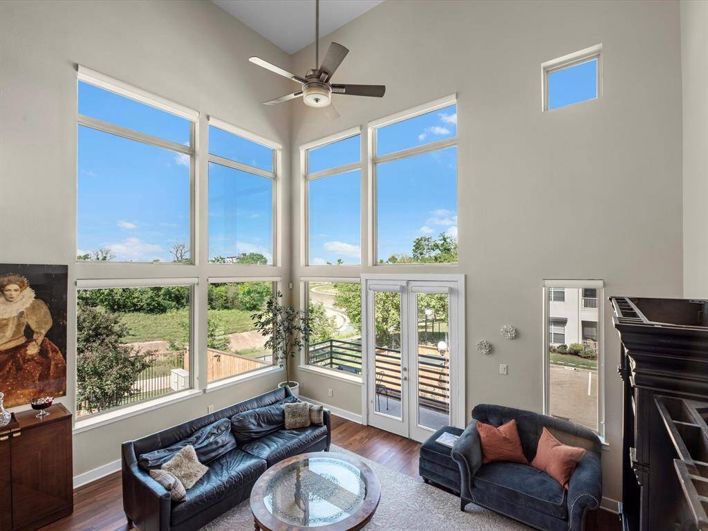 Light-filled living room with generous ceiling height and expansive windows that bring the outdoors in. The open layout and hardwood flooring create a comfortable, versatile space ideal for everyday living and hosting guests.