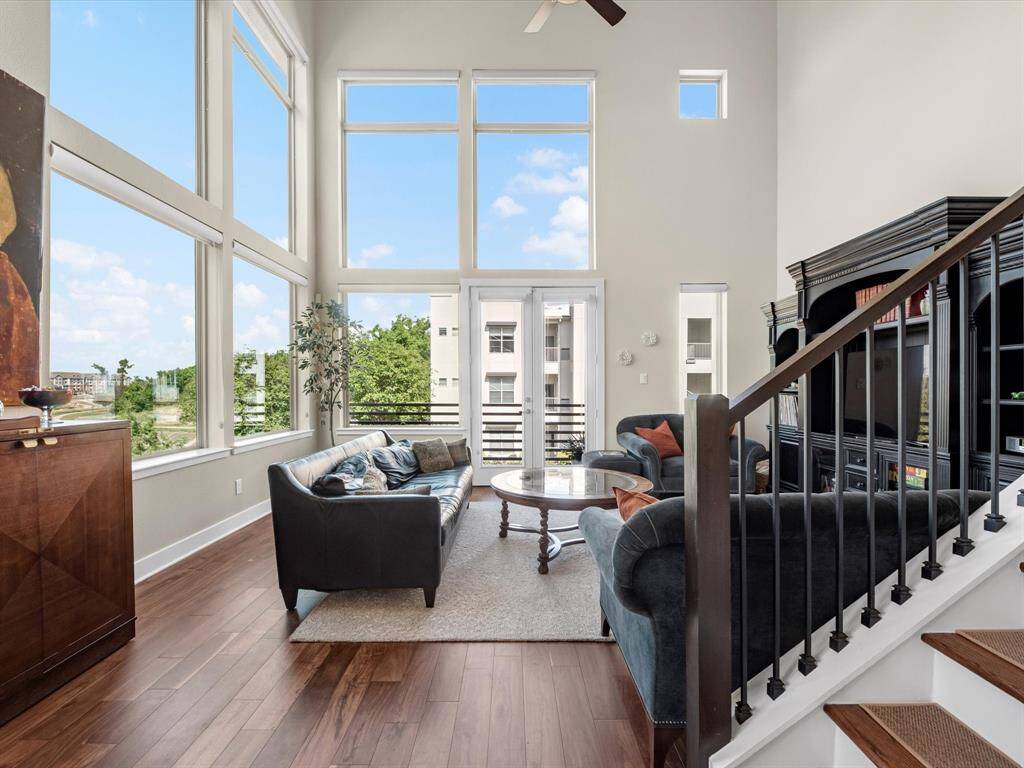 This living room feels warm and open, with natural light pouring in through tall windows. The rich walnut floors add depth and character, while the clean-lined staircase gives the space a modern edge. It’s an easy place to relax or host friends.