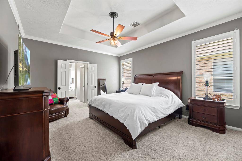 Step into your own personal sanctuary! This spacious primary bedroom features tray ceiling, crown molding, and plantation shutters for the ultimate relaxation space.