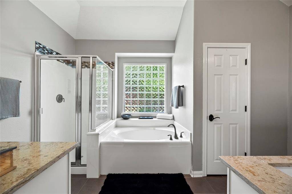 The primary bathroom boasts dual vanity, a relaxing jetted tub , and an enclosed shower for a spa-like experience.