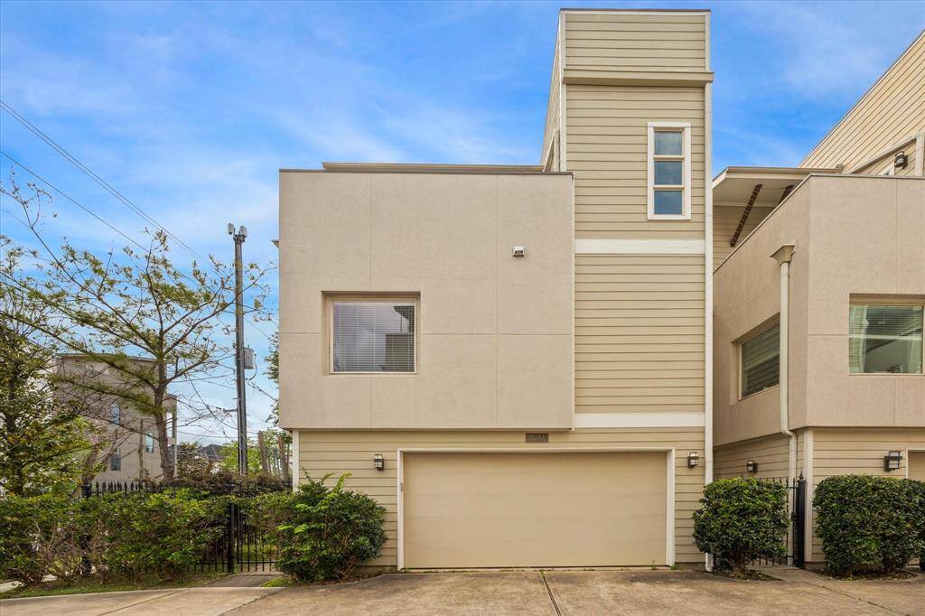 This modern single family home features a clean, minimalist exterior with a blend of light beige and cream siding. It includes a two-car garage and is surrounded by well-maintained shrubs, offering a neat and inviting appearance.