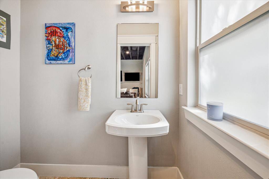 Half bath with a pedestal sink and a large window allowing natural light.