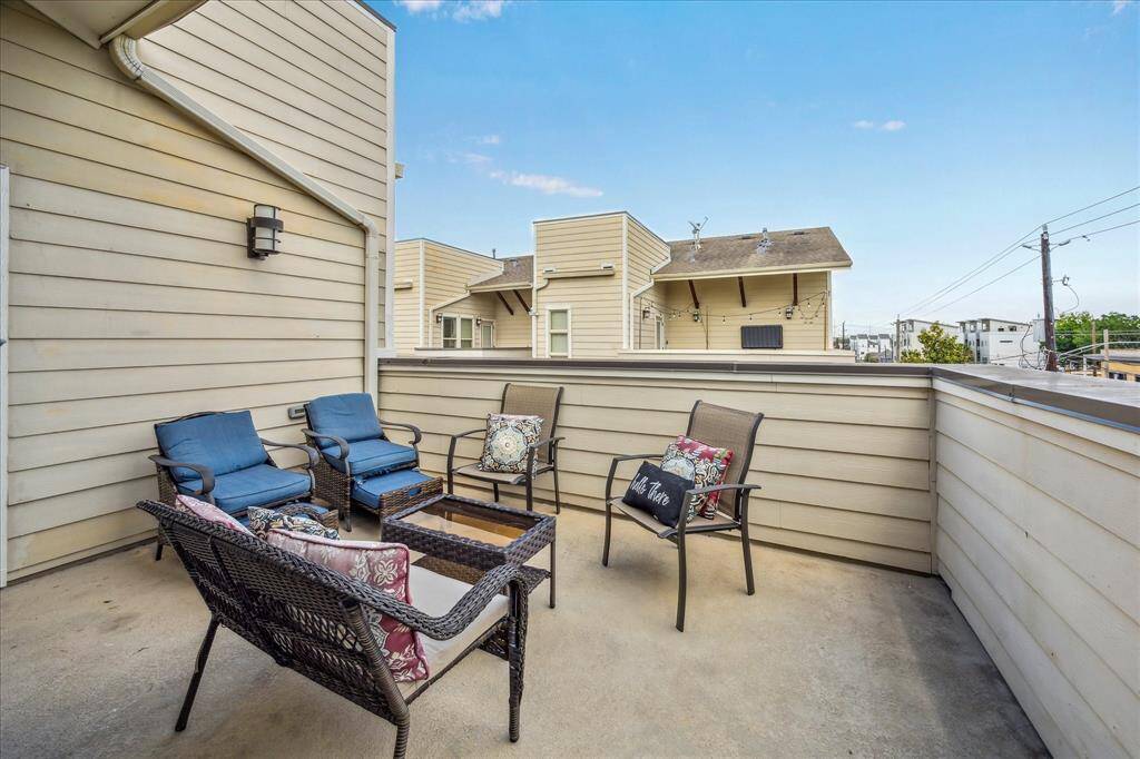 This spacious rooftop patio with comfortable outdoor seating, surrounded by privacy walls. It's a perfect spot for relaxing or entertaining with a view of the neighborhood.