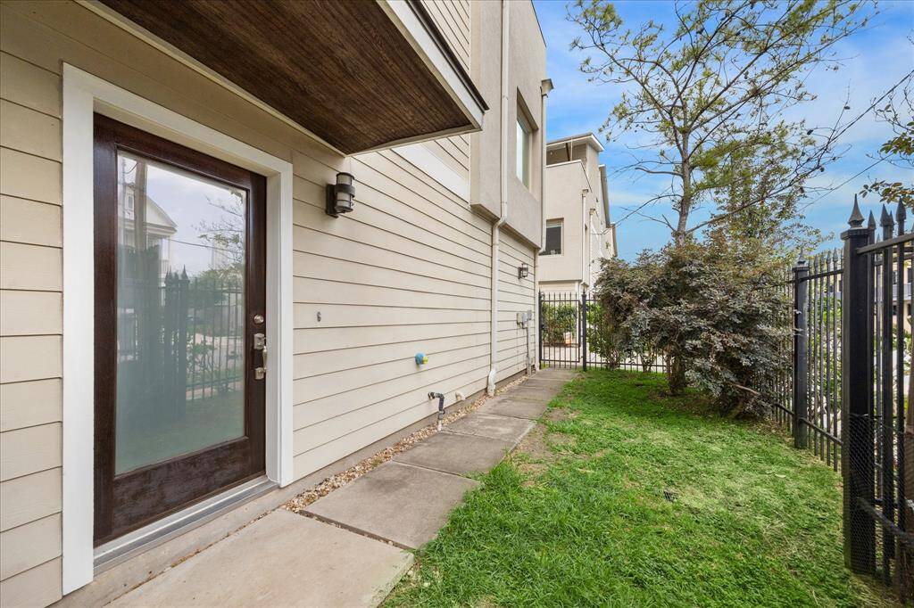 Beautiful entrance leading to a small fenced yard with a paved walkway and some greenery, providing a private outdoor space.