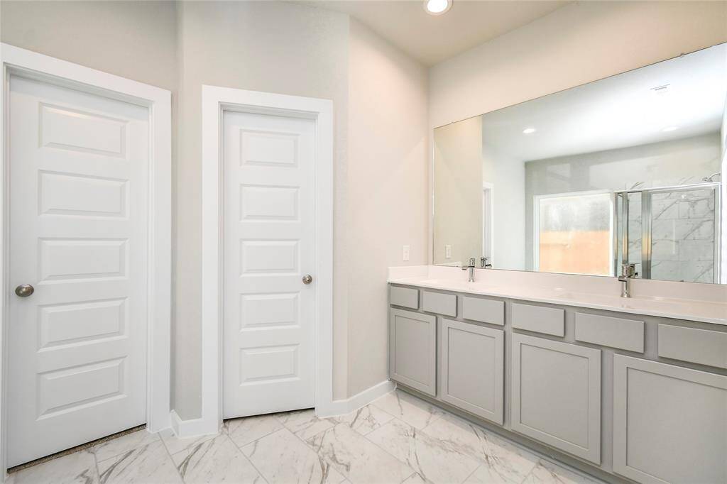 Escape to a spa-like oasis in this primary bathroom. Enjoy a walk-in shower with tile surround, a separate garden tub with custom detailing, and an elegant vanity featuring light countertops, modern hardware, and beautiful recessed lighting. Experience luxury and relaxation in every detail. Sample photo of completed home with similar floor plan. Actual colors and selections may vary.
