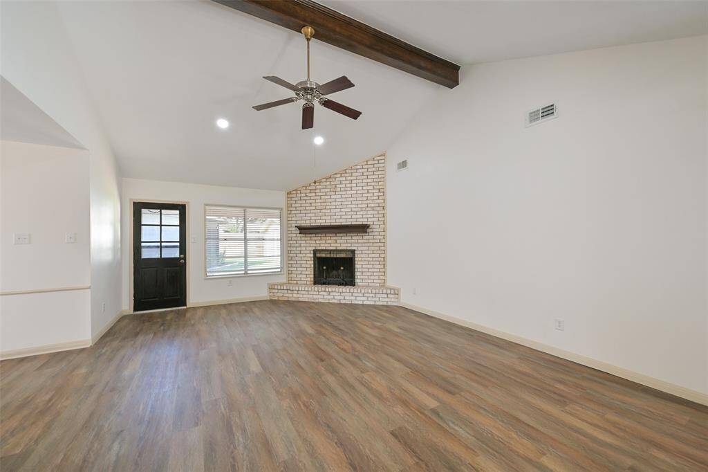 THE FAMILY ROOM IS VAULTED WITH DECORATIVE BEAM, CEILING FAN AND CORNER FIREPLACE ADDING WARMTH AND CHARM.
