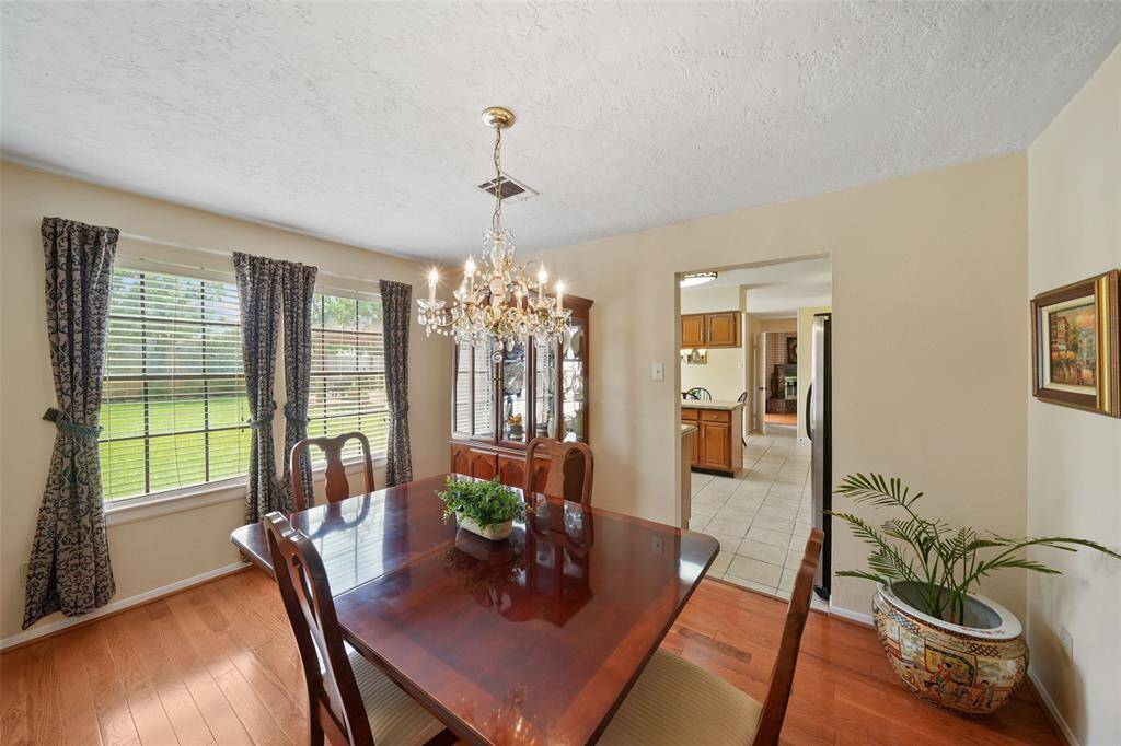 Experience elegance in this bright dining room, featuring a stunning chandelier and ample natural light through large windows.