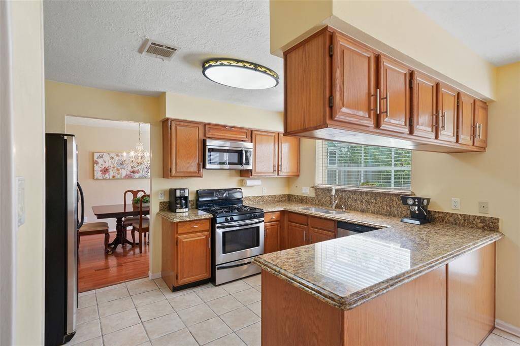 This kitchen boasts ample storage with sleek upper and lower cabinets, elegant granite countertops, and modern stainless steel appliances.
