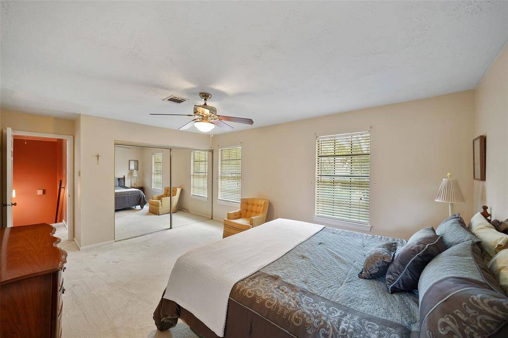 Spacious primary bedroom featuring abundant natural light, cozy carpeting, and elegant mirrored closets.