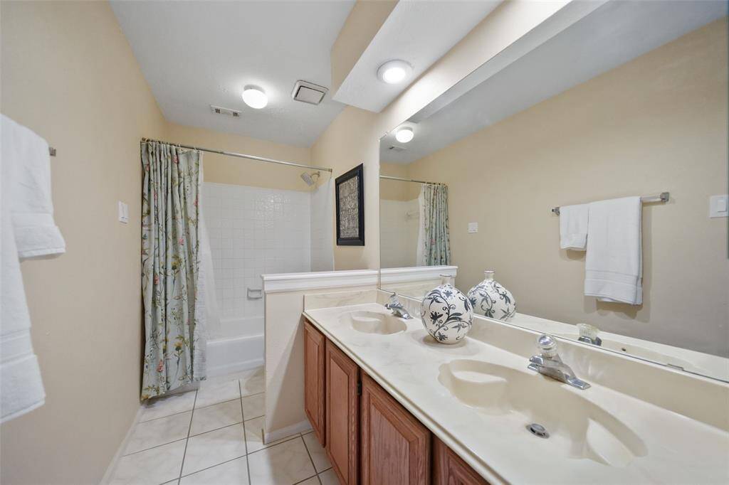 Spacious hall bath featuring a dual-sink vanity and a relaxing tub-shower combo.
