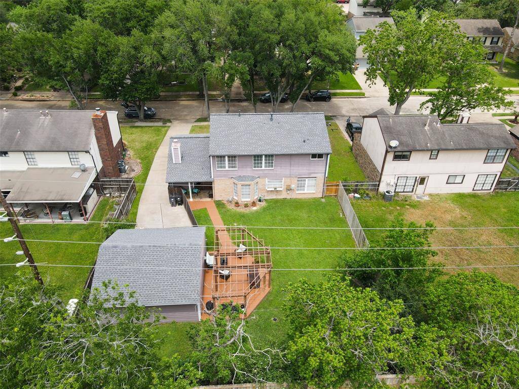 This photo shows a two-story home with a spacious backyard. It includes a large wooden deck and an additional structure, likely a garage or shed. The property is fenced and surrounded by greenery, providing privacy and a serene atmosphere.