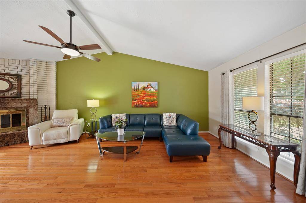 The family room boasts a vaulted ceiling, abundant natural light, elegant wood floors, and a marble gas fireplace.