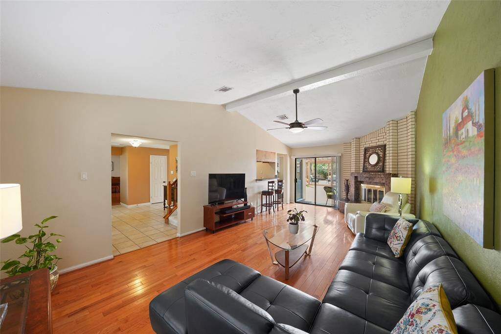 Spacious family room with hardwood floors, a cozy fireplace, and abundant natural light from large sliding doors.