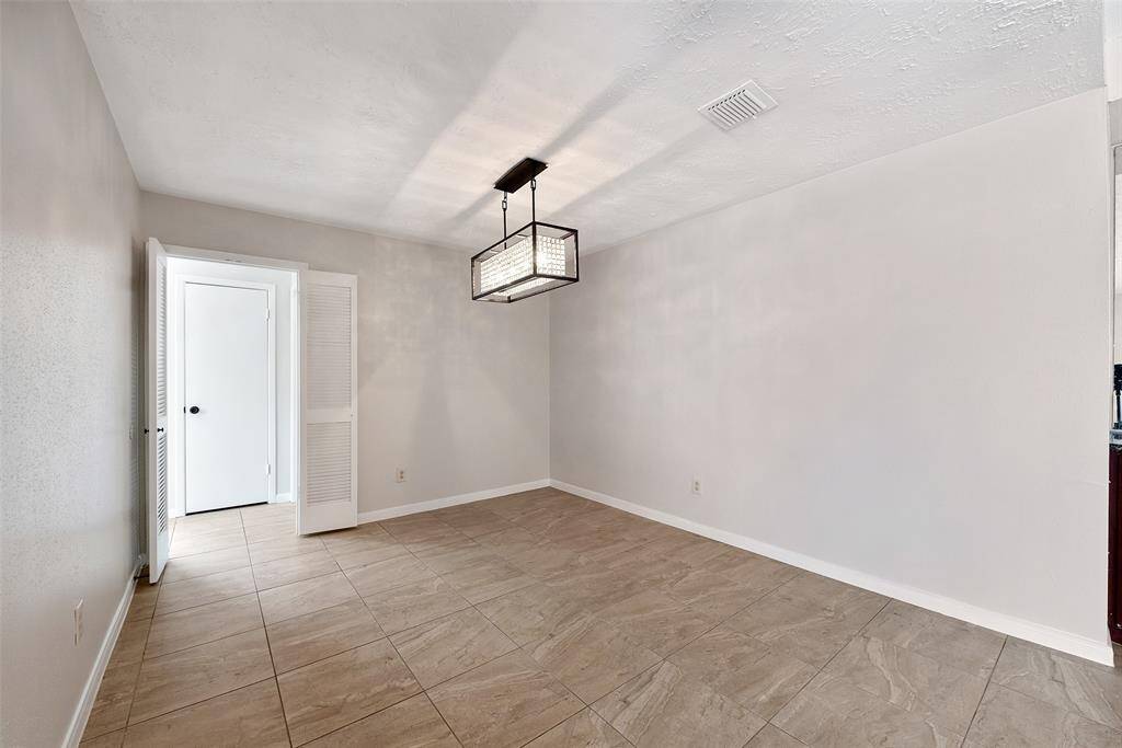 Bright and spacious dining area with a modern light fixture, next to a wet bar station and fireplace.