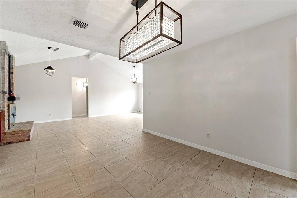 Bright and spacious dining area with a modern light fixture, next to a wet bar and fireplace.