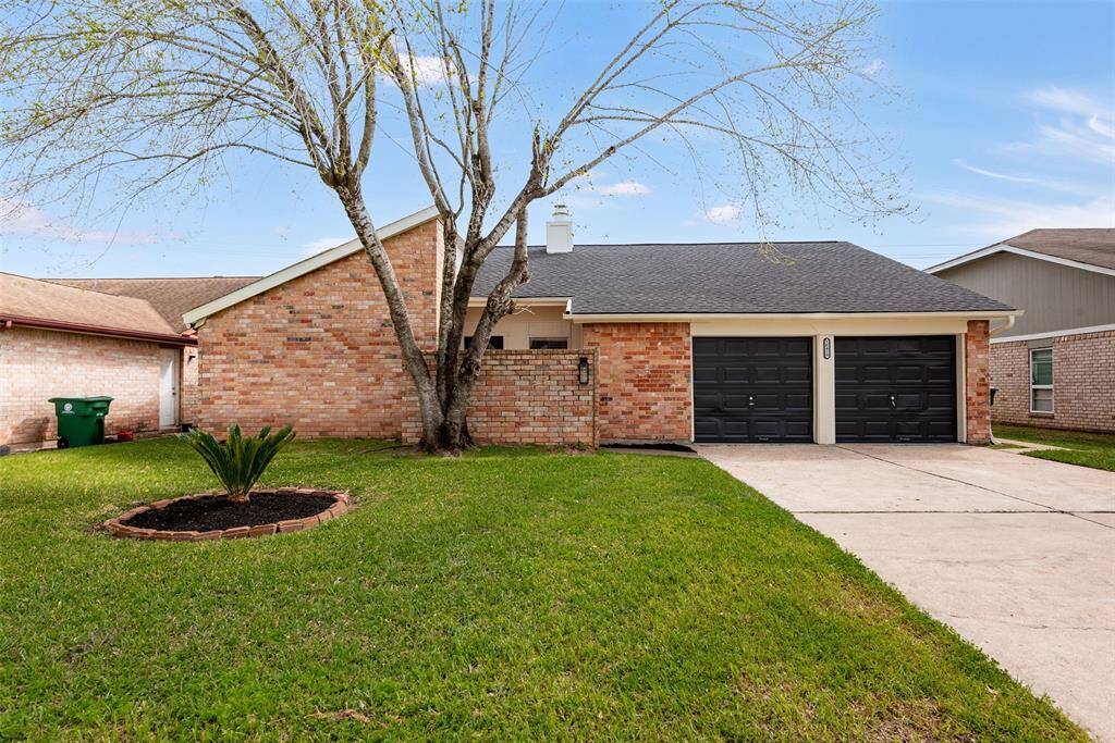 Charming single-story brick home with a welcoming front lawn, featuring a double garage and a mature tree adding character to the property.