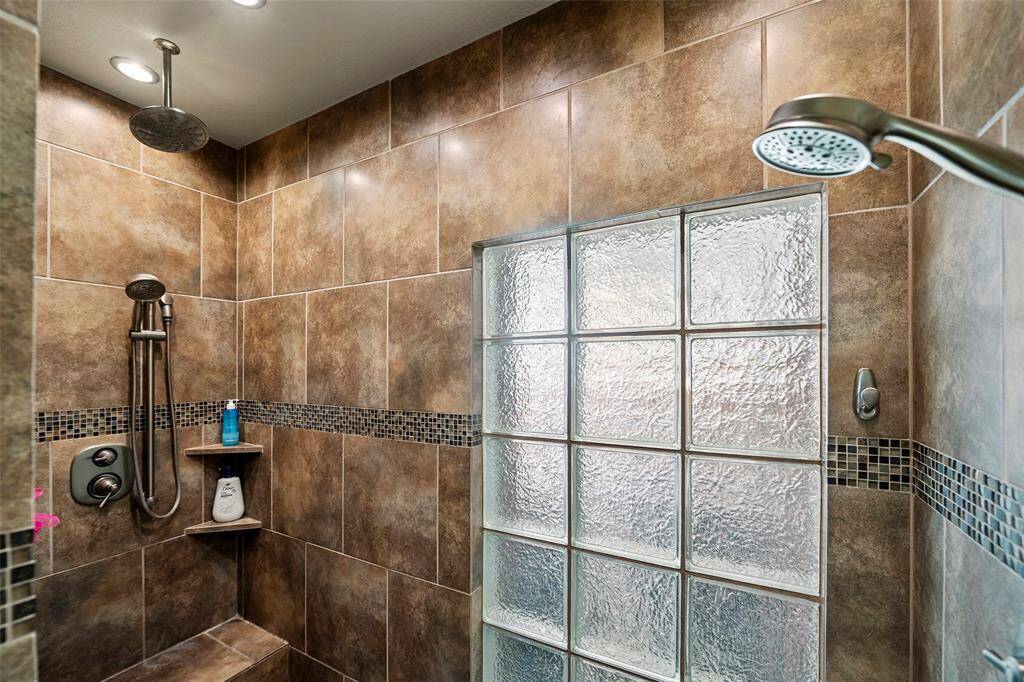 Step into this FABULOUS shower accented with decorative tile for an elevated look and glass block for natural lighting.  A rainfall showerhead is mounted along with 2 additional detachable showerheads for versatility.