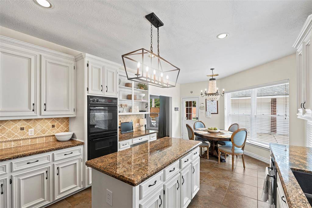 The light fixtures in this kitchen are the chef's kiss!  From being beautiful task lighting above the island, or the beaded fixture anchoring the charming breakfast room, we just love them both!  We'd be remiss if we failed to mention the open cabinets above the planning desk for display of those special items, cookbooks and the like.