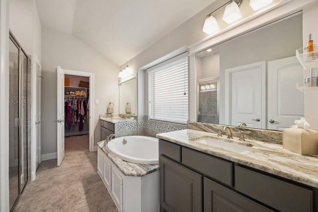 The primary suite offers a spa-like retreat with soaking tub, dual sinks, framed mirrors, and a walk-in closet.