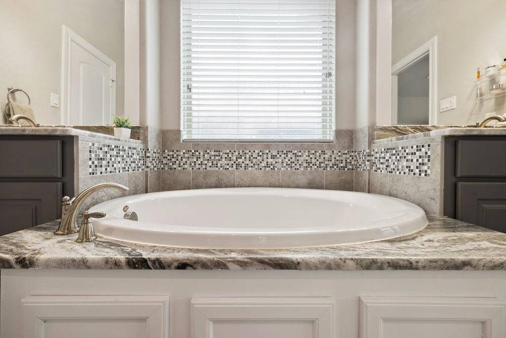 The primary suite offers a spa-like retreat with soaking tub, dual sinks, framed mirrors, and a walk-in closet.
