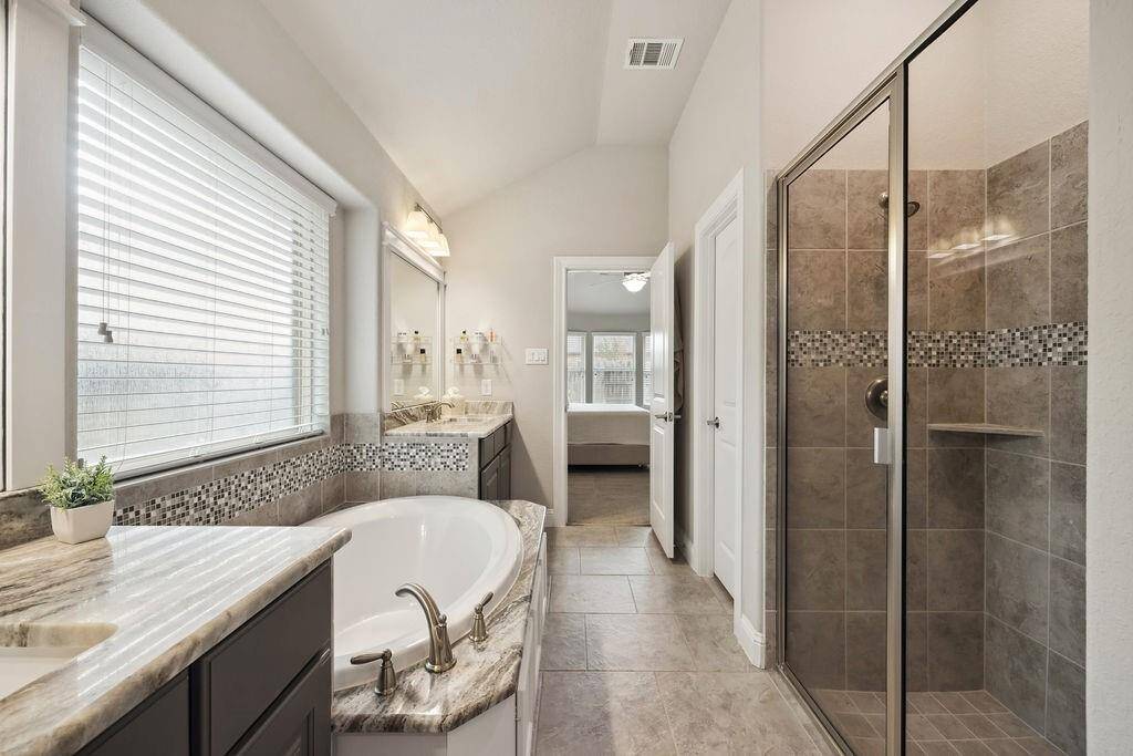 The primary suite offers a spa-like retreat with soaking tub, dual sinks, framed mirrors, and a walk-in closet.