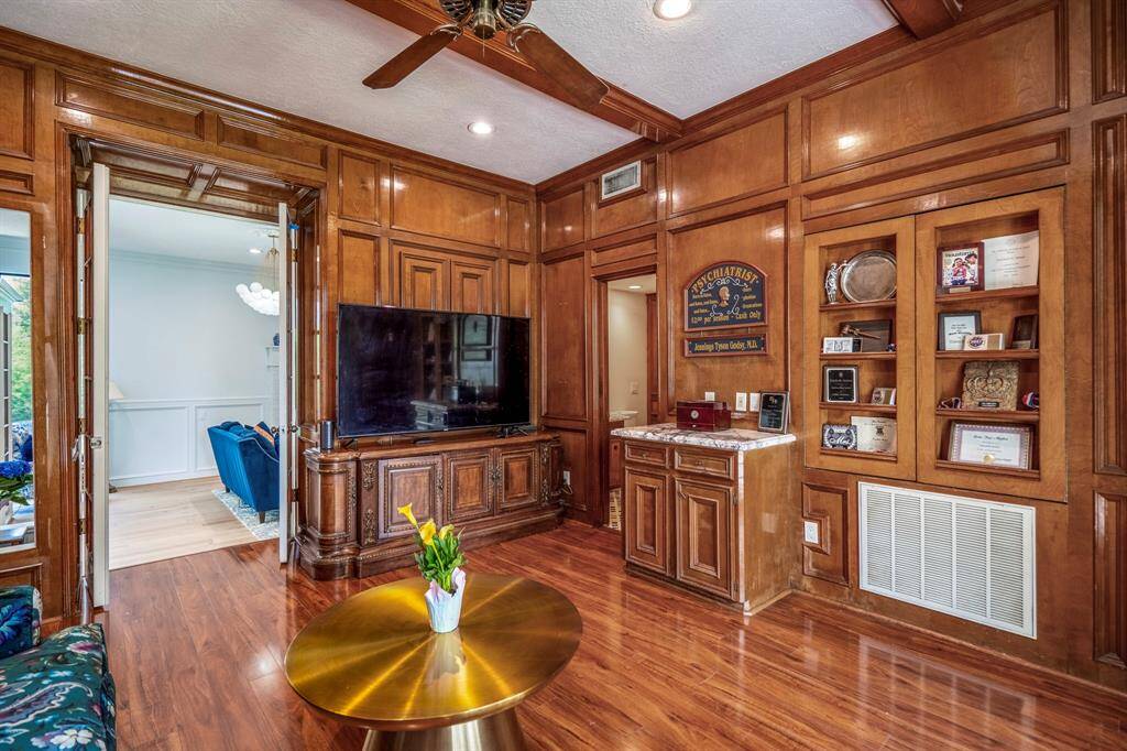 This bathroom in the study features a stylish marble countertop with a vessel sink and ornate framed mirror. It includes ample wooden cabinetry for storage and a modern toilet, complemented by a custom tiled floor.  The bathroom also features a full sized shower.