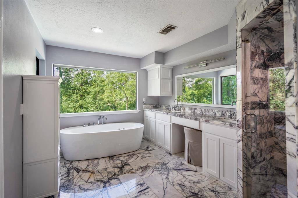 Modern bathroom design featuring a sleek marble-tiled shower and matching tile flooring. The space is complemented by neutral gray walls and recessed lighting, creating a bright and contemporary feel.