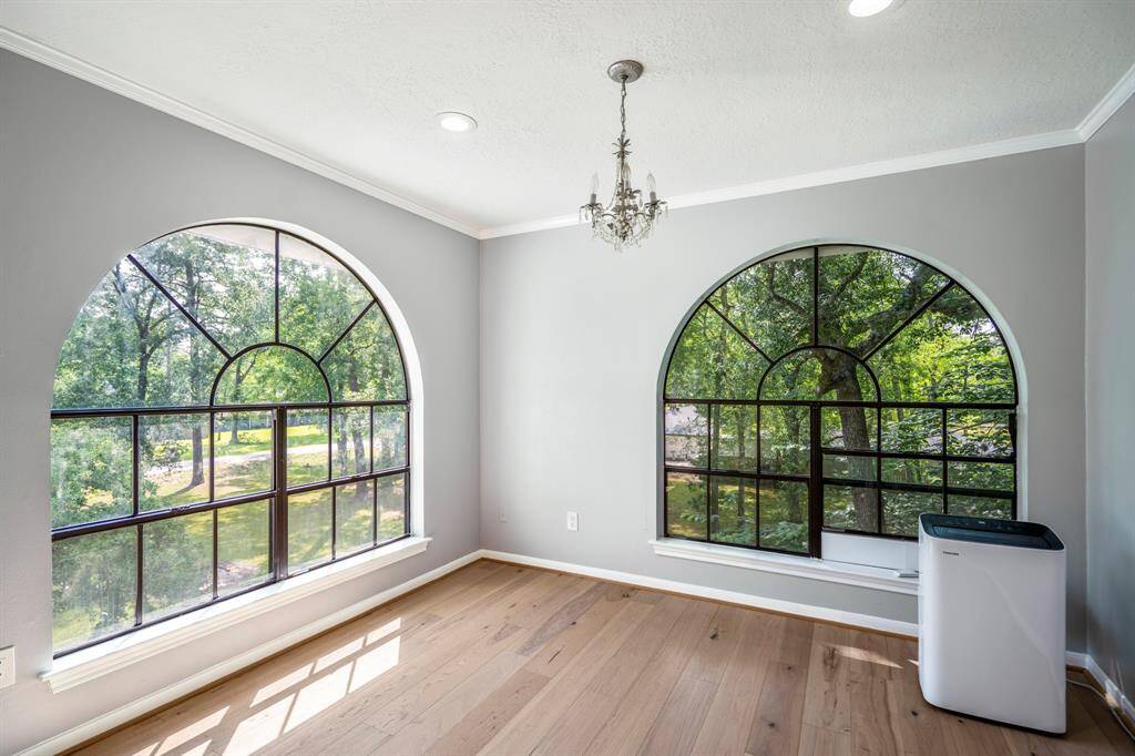 This spacious bedroom features a large window with a scenic view, allowing natural light to brighten the room. Large enough to accommodate a king size bed,  the light wood flooring adds warmth to the neutral wall tones.